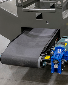 Chip conveyor attached to CNC machine for effective debris and material waste removal during machining operations.