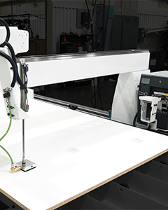 Close-up of an automated labeling sticker system on a CNC machine for efficient parts identification.