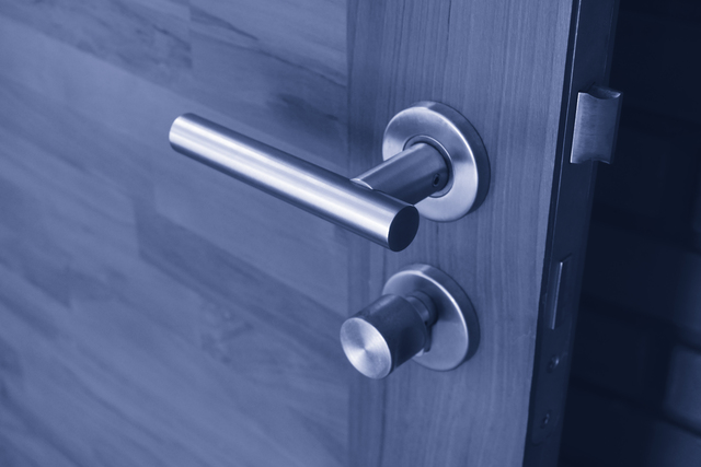 Modern stainless steel door handle on a wooden door, showcasing CNC machining applications in door and window manufacturing.
