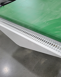 Dust Trough with Vacuum Port for Sawdust Collection on Parts Conveyor Close-up of a dust trough with a vacuum port at the end of a CNC parts conveyor for sawdust and debris collection.